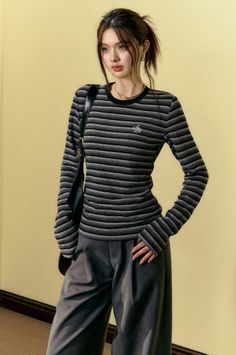 Woman in a striped long-sleeve shirt and wide-leg pants with a shoulder bag