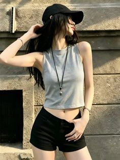 Woman in a black baseball cap and grey crop top with exposed midriff outdoors