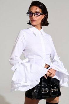 Woman in a white shirt with ruffle sleeves and black skirt in a studio