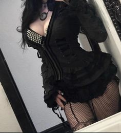 Woman in gothic attire with a studded bra and fishnet stockings