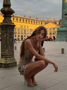 Woman in a mini dress squatting on a city street at golden hour