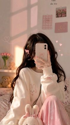 Person in a white sweatshirt and pink pants taking a selfie in a pink-themed room
