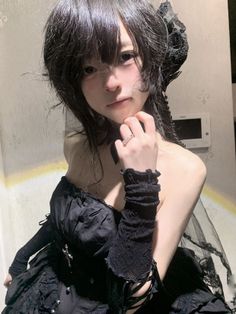 Person in a black gothic dress with lace gloves and a choker indoors