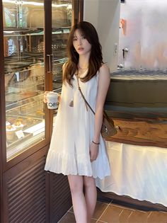 Woman in a white dress holding a coffee cup in a cafe