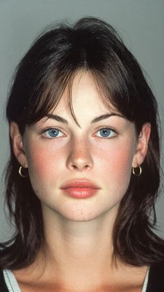 Woman with blue eyes and dark hair wearing gold hoop earrings