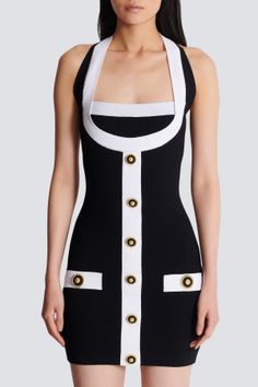 Woman in a black and white halter neck dress with gold buttons