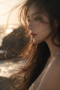 Woman with long hair in backlight at golden hour, looking to the side