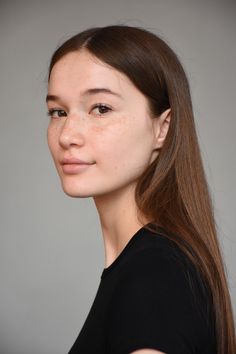 Young woman with long brown hair and freckles wearing a black shirt