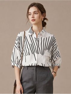 Woman in a white striped shirt and grey pants with a bun hairstyle