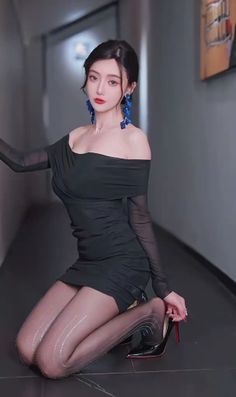 Woman in a black off-shoulder dress and sparkling tights posing indoors