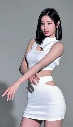Woman in a white crop top and mini skirt with cutouts posing in a studio
