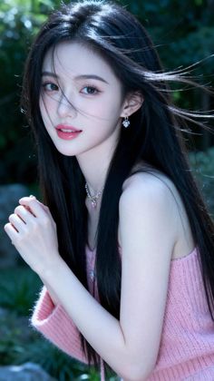 Woman with long black hair wearing a pink top and jewelry outdoors