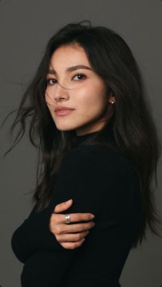 Woman with long dark hair wearing a black turtleneck and silver ring