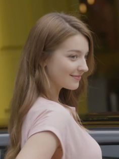 Woman with long hair in a pink t-shirt, smiling in profile view