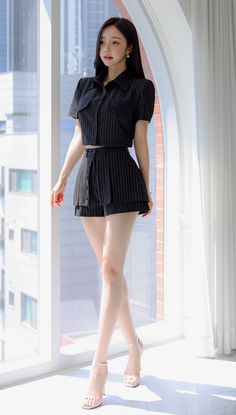 Woman in a pinstripe cropped top and shorts standing by a window