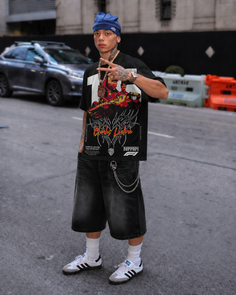Person in a blue beanie, graphic t-shirt, and baggy shorts on a street