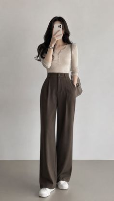 Woman in wide leg pants and a long sleeve top taking a mirror selfie