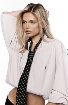 Blonde woman in an oversized jacket and striped tie with exposed skin