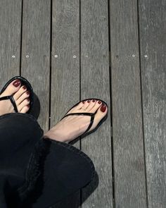 Feet with red nail polish and flip flops on a wooden floor