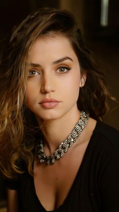 Woman with long hair and a necklace wearing a black top with cleavage