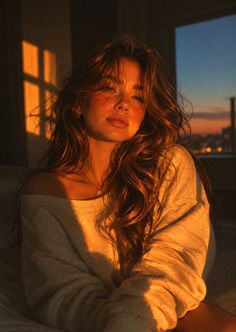 Woman with long wavy hair in an off-shoulder top bathed in golden hour light