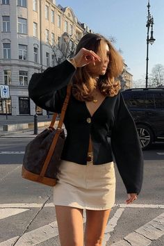 Woman in a black cardigan and mini skirt on a city street