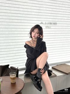 Woman with short hair wearing a black shirt and choker, sitting indoors