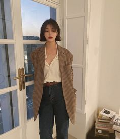 Woman with short hair wearing a plaid blazer and jeans indoors