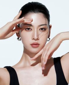 Woman with black hair and hoop earrings posing with hands near her face