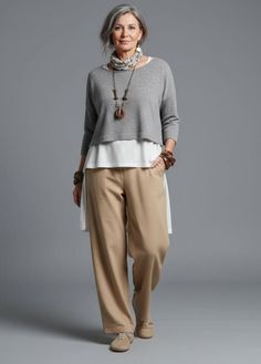Woman with gray hair wearing layered clothing and wide leg pants