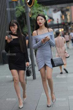 Two women in mini dresses walking on a city street