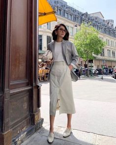 Woman in a blazer and midi skirt standing on a city street
