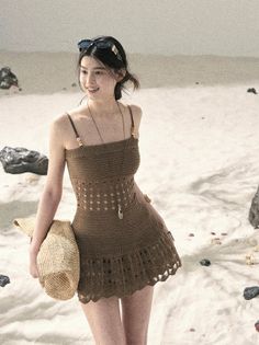 Woman in a brown crochet dress and sunglasses on a sandy beach
