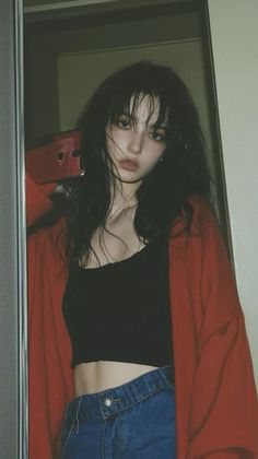 Woman with long dark hair wearing a red cardigan and black crop top