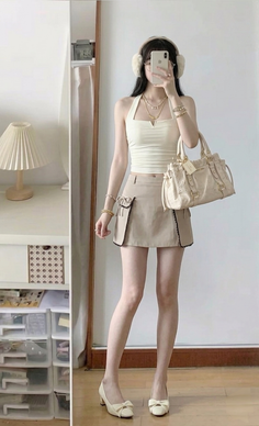 Woman in a halter top and mini skirt holding a handbag indoors