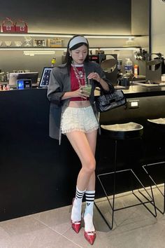 Woman in a red crop top and ruffle shorts with a blazer and high heels indoors