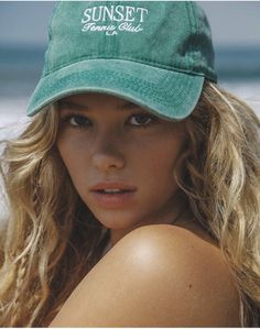 Woman with blonde wavy hair wearing a green cap outdoors