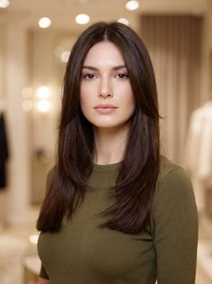 Woman with long dark hair wearing a green top indoors