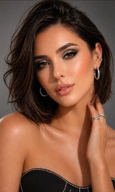 Woman with short dark hair and sparkling makeup wearing jewelry