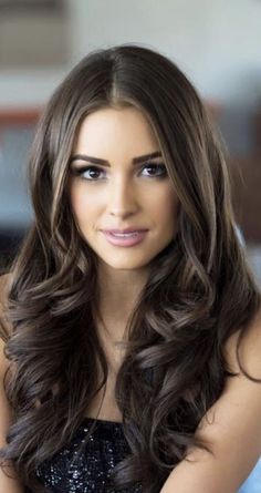 Woman with long wavy dark brown hair wearing a black top