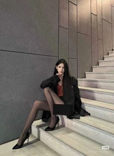 Woman in a black blazer and red top sitting on stairs
