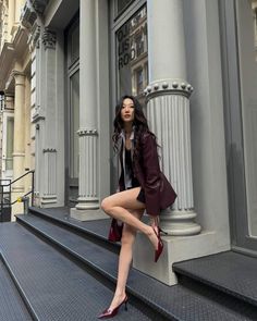 Woman in a burgundy blazer and red heels posing on city steps