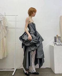 Person in a gray strapless dress and lace pants with silver boots in an indoor setting