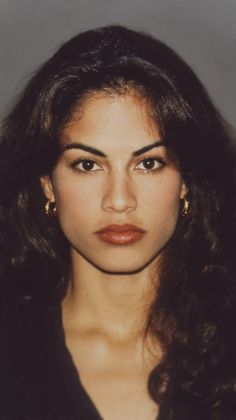 Woman with long dark hair and gold hoop earrings looking directly at the viewer
