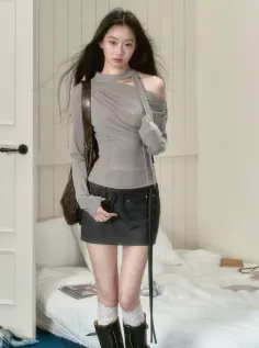 Woman with long dark hair wearing an off-shoulder top and mini skirt indoors