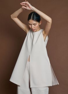Woman in a light-colored sleeveless top with a split front and high neck