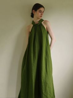 Woman in a green halter neck dress standing indoors with soft lighting