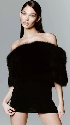 Woman in a black fur stole and dress with exposed shoulders in a studio