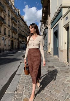 Woman in a polka dot skirt and cardigan walking on a city street