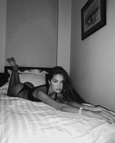 Woman in lingerie lying on a bed in a bedroom, looking at the camera